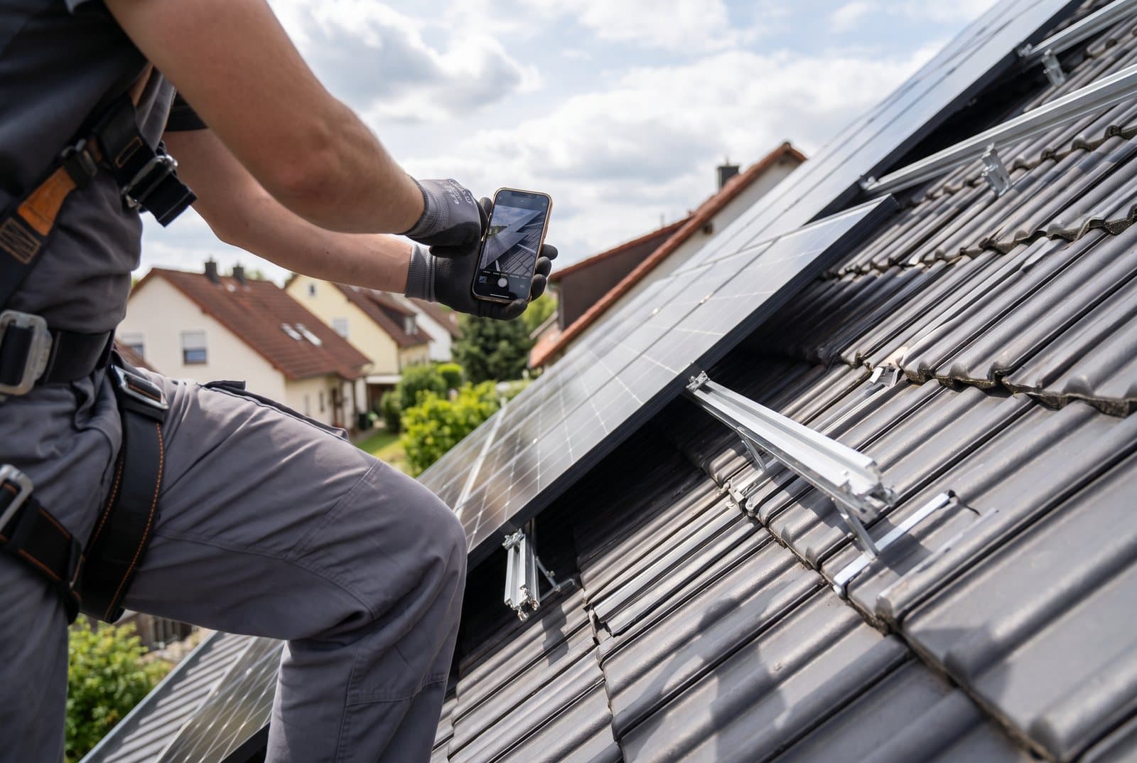 Monteur fotografiert die frisch montierten Solarmodule auf dem Ziegeldach